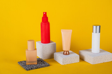 Cosmetic pink bottle. Womens cosmetic accessory for makeup with stylish props on yellow background.