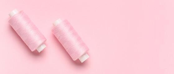 Spools of threads on pink background with space for text, top view