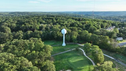 Water Tower At East Mountain Golf Course Surrounded By Green Forest In Waterbury, Connecticut, USA. - aerial shot