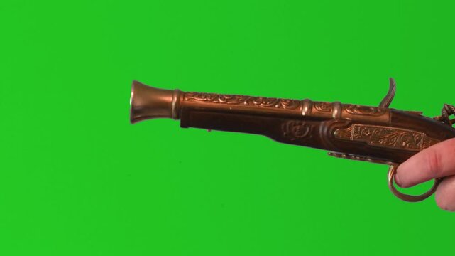 Load and fire an antique pistol with green screen backdrop in a controlled setting