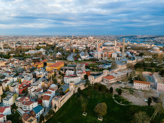 A stunning aerial view of the Topkapi Palace walls and the Hagia Sophia in Istanbul, Turkey, bathed in warm morning light with the old town stretching into the background.

