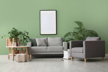 Interior of stylish room with grey sofa, armchair and blank frame