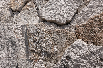 Close-up of weathered coastal rock face showing deep fissures and rough textures