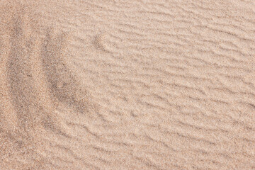 Close-up view of rippled sand and sunlit grains forming gentle dunes
