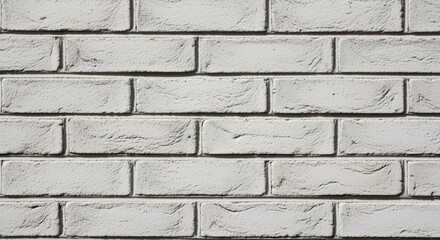 Obraz premium A closeup view of a plain white brick wall with a uniform, textured surface. The bricks are arranged in a regular pattern, creating a clean and minimalist architectural aesthetic.