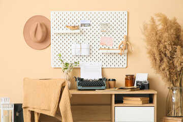 Workplace with vintage typewriter and vase with pampas grass near beige wall in room