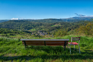 un banc et une chaise face à un panorama auvergnat sur la ville de Saint-Nectaire