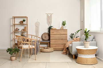 Interior of stylish living room with grey sofa, wooden dresser and armchairs