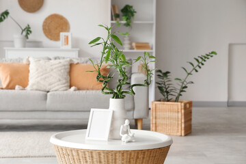 Vase with bamboo stems, figurine and blank frame on coffee table in living room, closeup