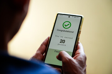 Man got a congratulatory message on his phone for earning points after purchasing online. Selective focus, customer loyalty program in e-commerce concept.