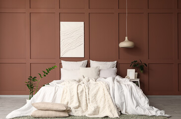 Interior of stylish bedroom with cozy bed, houseplants and painting