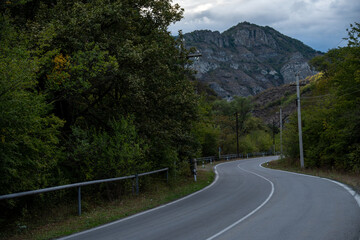 Curvy mountain road surrounded by green forest and dramatic cliffs