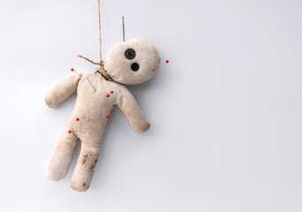 Hanging creepy curse voodoo doll was punished with a needle and pins and hanged on white background copy space.