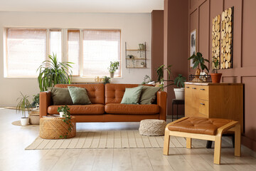 Interior of stylish living room with brown sofa, wooden cabinet and houseplants