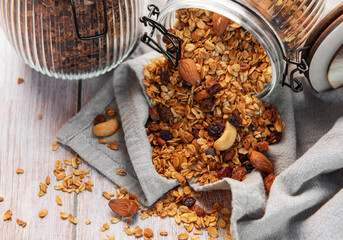 Granola mix with oats, nuts, and dried fruits spilling onto a grey napkin