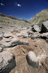 A small river flowing through a valley between mountains. A muddy mountain river flowing through a rocky gorge
