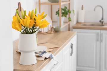 Vase with beautiful lily flowers on counter in kitchen, closeup