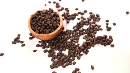 Roasted Coffee Beans Overflowing from a Wooden Bowl on White