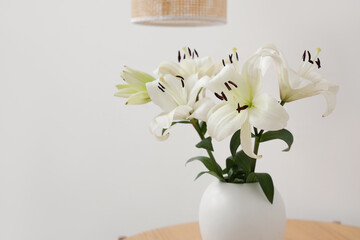 Vase with beautiful lily flowers on coffee table near white wall, closeup