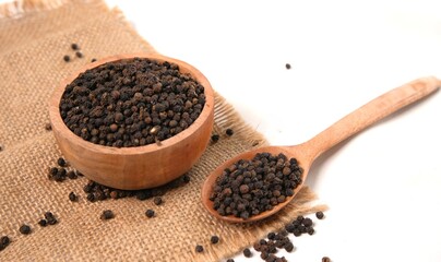 Aromatic Black Peppercorns in Wooden Bowl and Spoon on Burlap