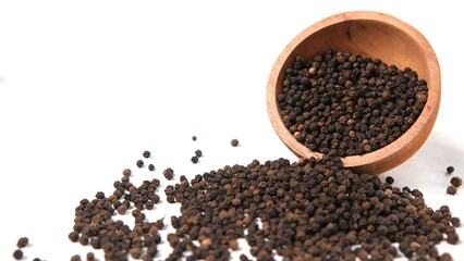 Black Peppercorns Overflowing from Wooden Bowl on White Background