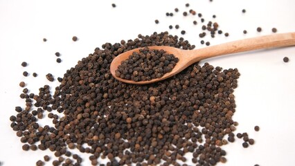 Black Peppercorns with Wooden Spoon on White