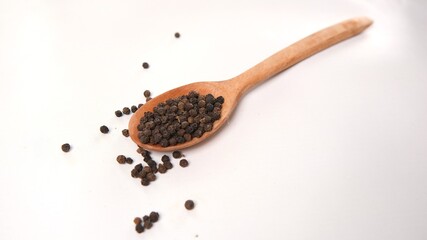Wooden Spoon with Black Peppercorns on White