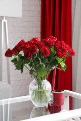 Naklejka na ściany i meble Vase with beautiful red roses and candles on glass coffee table in stylish living room Naklejka na ściany i meble Vase with beautiful red roses and candles on glass coffee table in stylish living room
