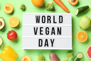 Different fresh fruits, vegetables and board with text WORLD VEGAN DAY on green background
