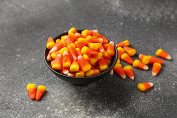 Bowl with sweet candy corns on dark background. Halloween celebration
