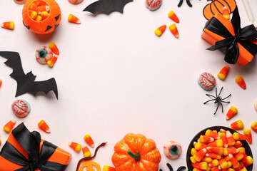 Frame made of sweet candy corns with gift boxes and different decorations on white background. Halloween celebration