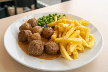 Meatballs with french fries, green peas, bechamel sauce and cranberry jam