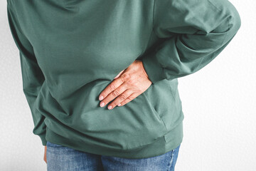 Person in green sweatshirt touching side with hand, expressing pain or discomfort, concept of health problem, side ache, kidney or liver disease, muscle strain and body pain awareness