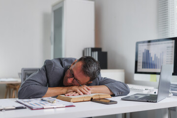 Obraz premium Businessman sleeping on office desk experiencing burnout