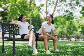Naklejka premium Young women friends relaxing talking park bench