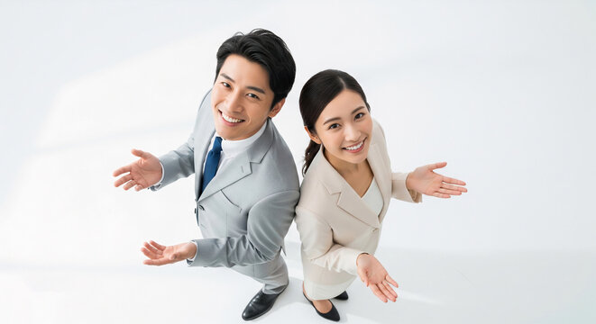 Two Asian business professionals smiling and presenting with open hands on white background