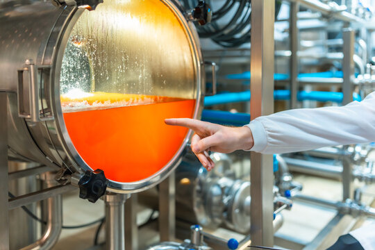 Brewery worker checking beer fermentation process in tank - Powered by Adobe