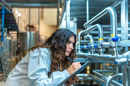 Woman inspecting beer factory pipes during quality control