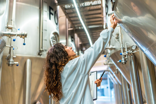 Woman inspecting beer fermentation tank at brewery factory