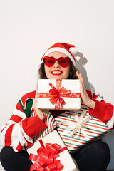 Santa helper wearing sunglasses holding stack of striped wrapped holiday presents