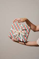 Hands carefully presenting a beautifully wrapped festive Christmas gift box