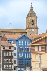 Fototapeta premium Traditional Colorful Buildings with Church Tower in Bermeo, Basque Country Spain, Blue Enclosed Balconies, Stone Bell Tower Historic Buildings