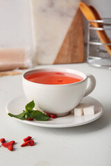 Cup of hot goji tea with mint and cubes of sugar on white background