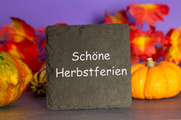 Schieferplatte mit der Aufschrift SCHÖNE HERBSTFERIEN und herbstliche Dekoration