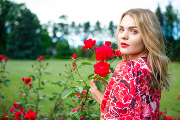 Naklejka premium Positive Winsome Fashion Girl in Fragrant Pink Flowers in Summer Blossom Park In a Blooming Garden as Fashion, Cosmetics and Perfumes With Blond Hair.