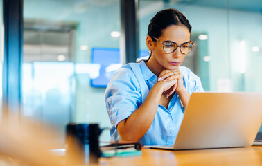 Businesswoman focusing intently on her laptop in a professional office setting