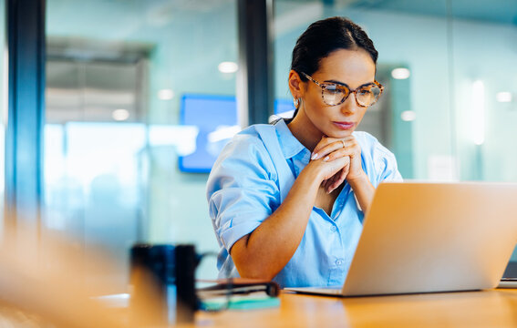 Fototapeta Businesswoman focusing intently on her laptop in a professional office setting