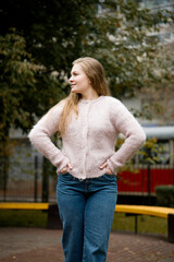 Obraz premium young blonde beautiful woman with long hair in pink handmade sweater posing in the autumn park