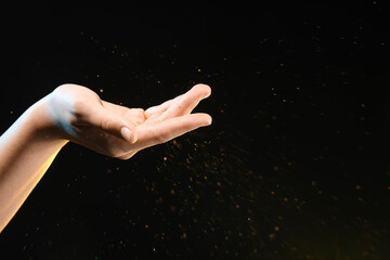 Female hand with energy sparkles on black background