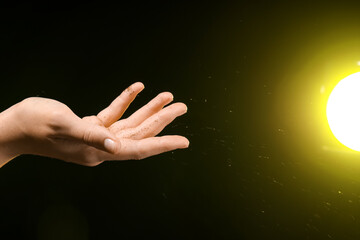 Female hand with energy sparkles and yellow light on black background